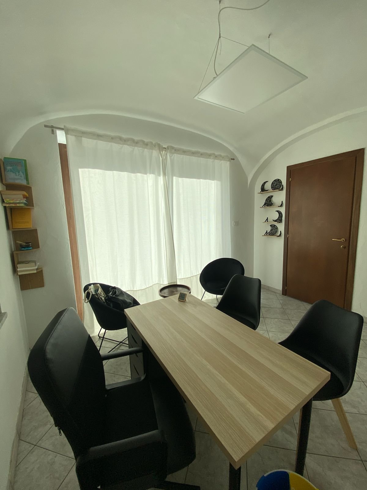 Studio di psicoterapia a Bussoleno per adulti, arredato con tavolo in legno chiaro e sedie nere, ambiente accogliente.